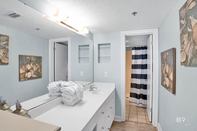 bathroom with vanity, a textured ceiling, hardwood / wood-style flooring, and curtained shower