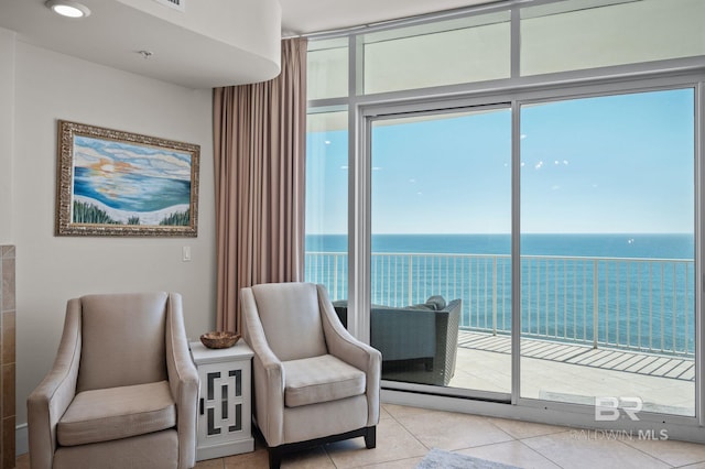 living area with light tile patterned floors, a wall of windows, and a water view