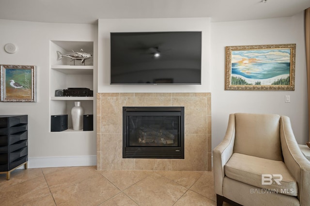 living room featuring built in features, a tile fireplace, tile patterned flooring, and baseboards