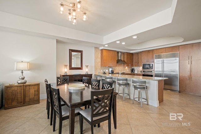 dining room with light tile patterned floors, a tray ceiling, a notable chandelier, and recessed lighting