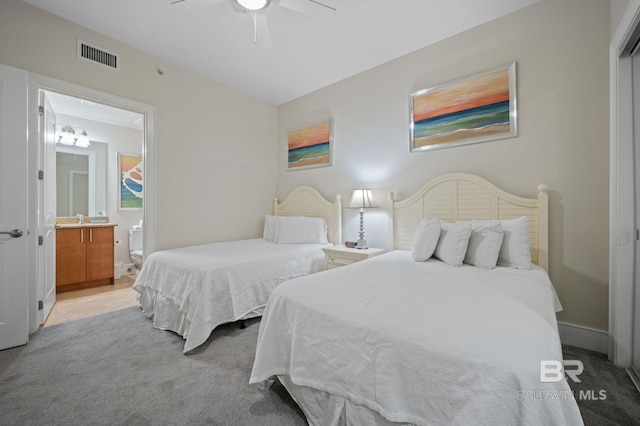 bedroom with visible vents, a ceiling fan, light carpet, ensuite bath, and baseboards