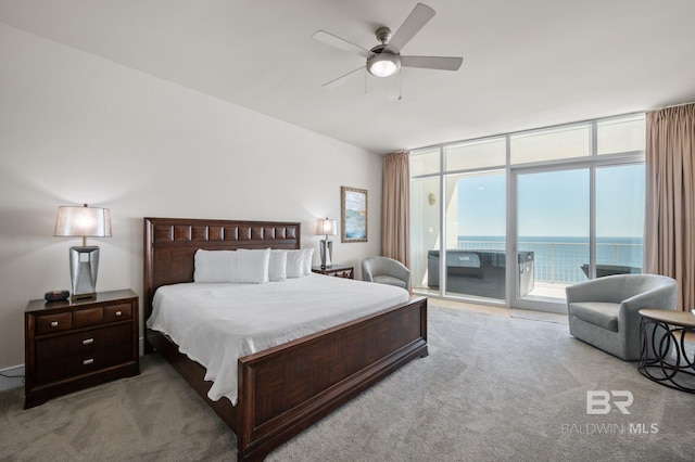 bedroom featuring a water view, a ceiling fan, access to exterior, a wall of windows, and carpet