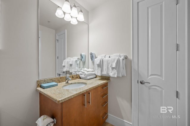 bathroom featuring an inviting chandelier, vanity, and baseboards