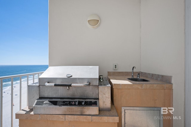 view of patio / terrace with a beach view, a water view, a grill, a sink, and exterior kitchen