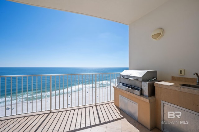 balcony with a water view, a sink, exterior kitchen, and area for grilling