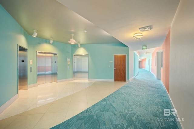 hallway featuring elevator, visible vents, and tile patterned floors