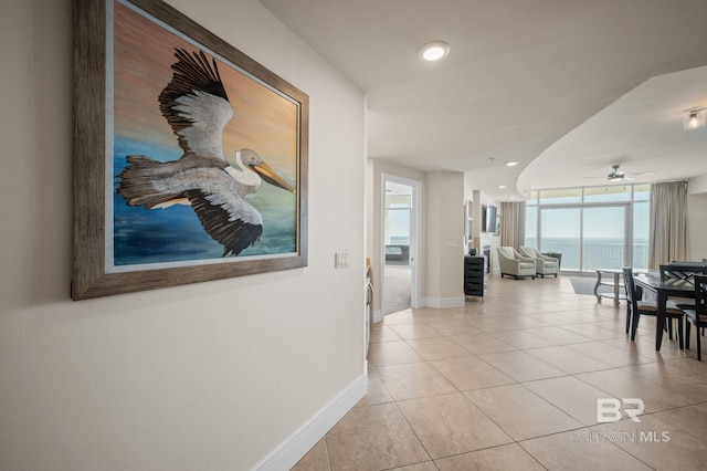 hall featuring light tile patterned floors, expansive windows, and baseboards