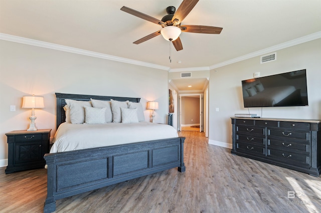 bedroom with visible vents, crown molding, baseboards, and wood finished floors