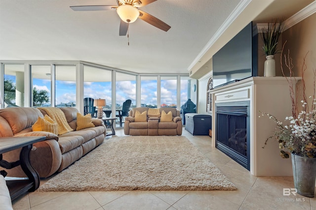 living room featuring crown molding, light tile patterned flooring, a fireplace, and ceiling fan