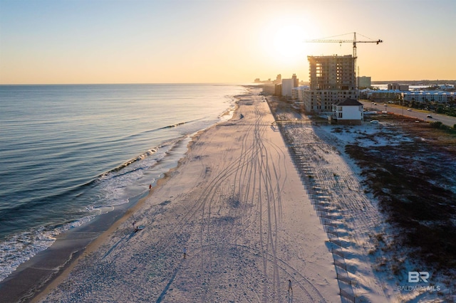 aerial view at dusk with a water view and a beach view