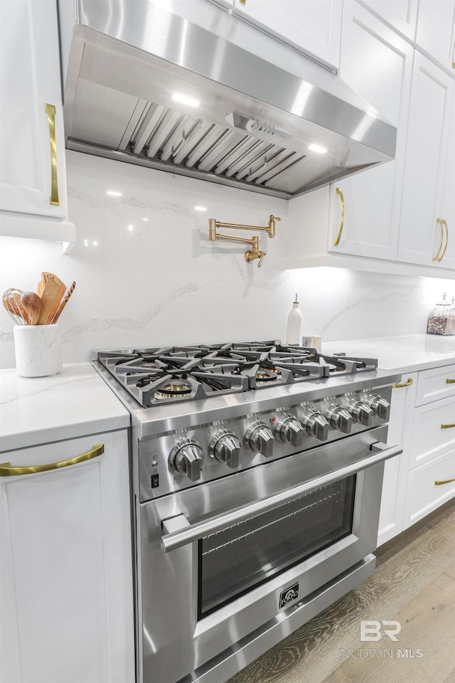 845 Inlet Cir, Gulf Shores, AL 36542 - kitchen featuring high end stove, extractor fan, white cabinets, and wood finished floors