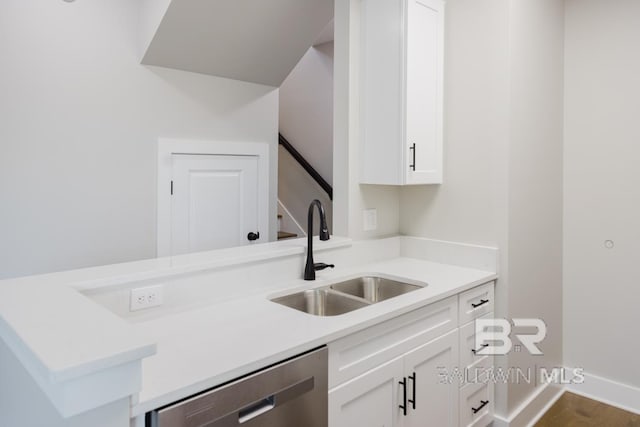 kitchen featuring stainless steel dishwasher, sink, and white cabinets