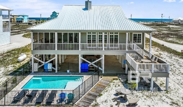 back of property with a sunroom, a patio, and a pool side deck with water view