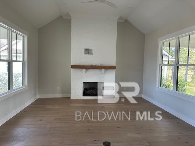 unfurnished living room with hardwood / wood-style floors, vaulted ceiling, and a wealth of natural light