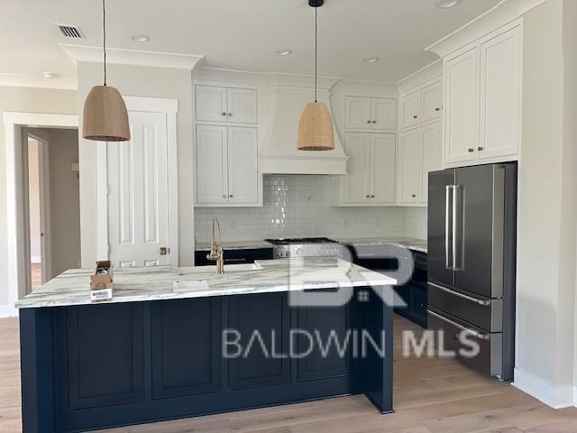 kitchen featuring white cabinetry, hanging light fixtures, stainless steel appliances, and light wood-type flooring