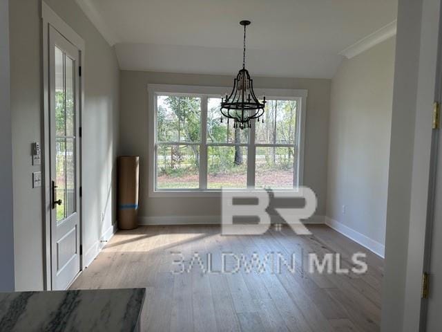 unfurnished dining area featuring an inviting chandelier and light hardwood / wood-style floors