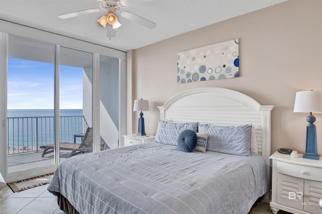 tiled bedroom with a ceiling fan, access to exterior, and a water view