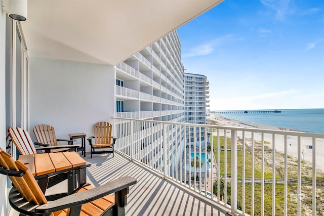 balcony with a water view and a view of the beach