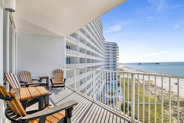 balcony featuring a view of the beach and a water view