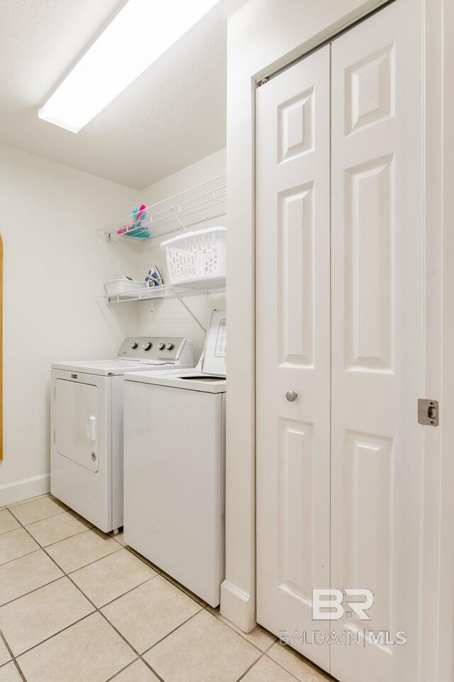 401 E Beach Blvd Unit 1302, Gulf Shores, AL 36542 - laundry area with washer and dryer, laundry area, light tile patterned floors, and baseboards
