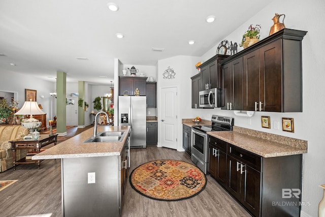 23038 Ridgewood Dr, Robertsdale, AL 36567 - kitchen featuring appliances with stainless steel finishes, a sink, wood finished floors, a kitchen island with sink, and dark brown cabinetry
