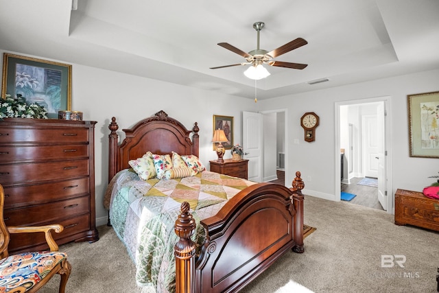 23038 Ridgewood Dr, Robertsdale, AL 36567 - bedroom featuring a tray ceiling, light carpet, baseboards, connected bathroom, and a ceiling fan
