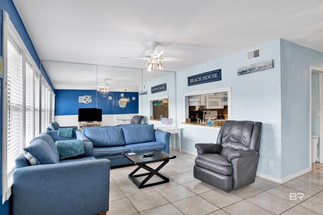 living room featuring ceiling fan with notable chandelier and light tile patterned floors