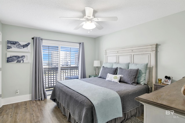 bedroom with light wood-style flooring, a textured ceiling, baseboards, and ceiling fan