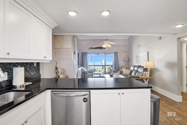 kitchen featuring visible vents, backsplash, stainless steel dishwasher, dark countertops, and a peninsula