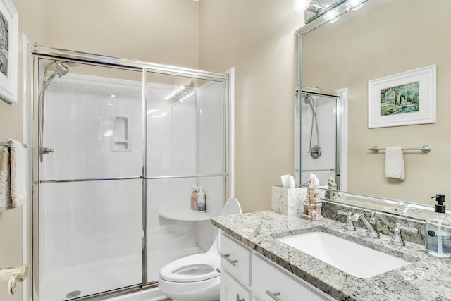 bathroom featuring toilet, a shower with shower door, and vanity