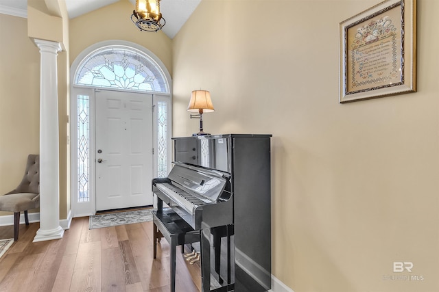 foyer entrance featuring decorative columns, vaulted ceiling, and wood-type flooring