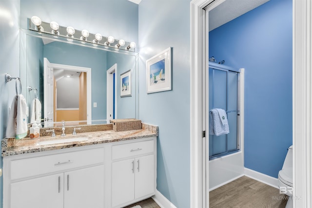 full bathroom featuring vanity, toilet, hardwood / wood-style flooring, and bath / shower combo with glass door