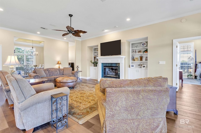 living room featuring ornamental molding, light wood-type flooring, and plenty of natural light