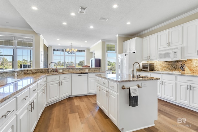 kitchen with white cabinets, a textured ceiling, a wealth of natural light, light hardwood / wood-style flooring, and white appliances