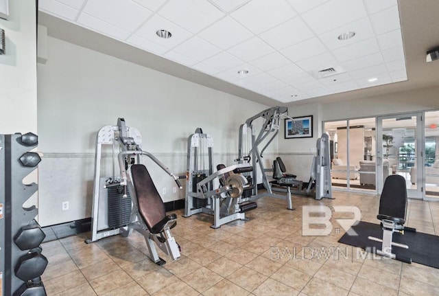 exercise room featuring a drop ceiling, french doors, and tile patterned flooring