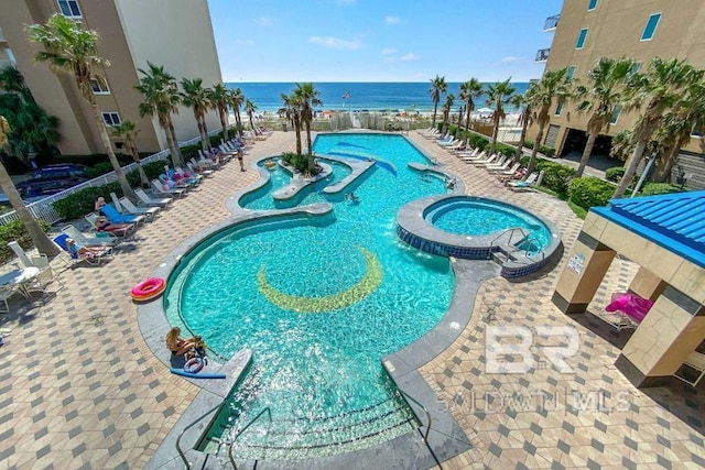 view of swimming pool featuring a community hot tub, a patio, and a water view