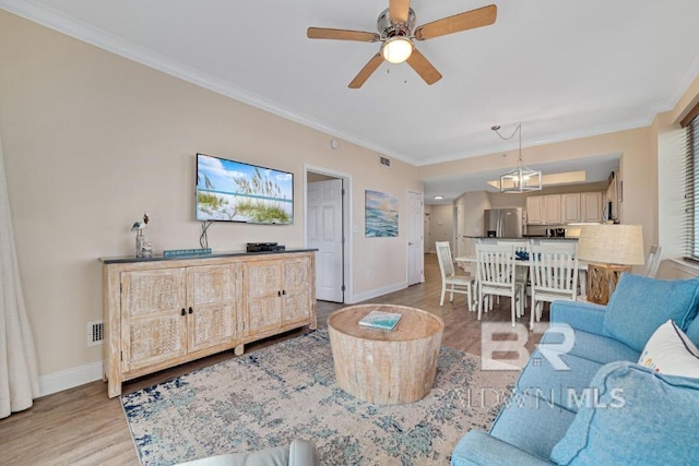 living room featuring light hardwood / wood-style floors, crown molding, and ceiling fan with notable chandelier