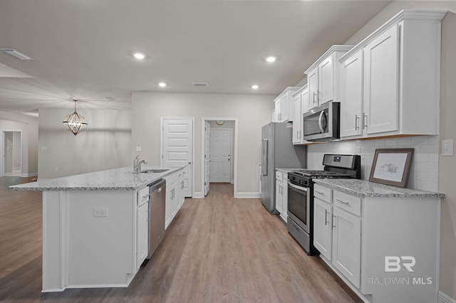 24884 Smarty Jones Cir, Daphne, AL 36526 - kitchen with appliances with stainless steel finishes, light wood finished floors, white cabinets, a center island with sink, and recessed lighting