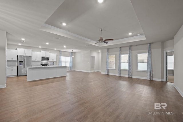 24884 Smarty Jones Cir, Daphne, AL 36526 - unfurnished living room with a raised ceiling, crown molding, ceiling fan, light wood-style floors, and recessed lighting