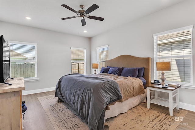 bedroom with multiple windows, ceiling fan, and wood-type flooring