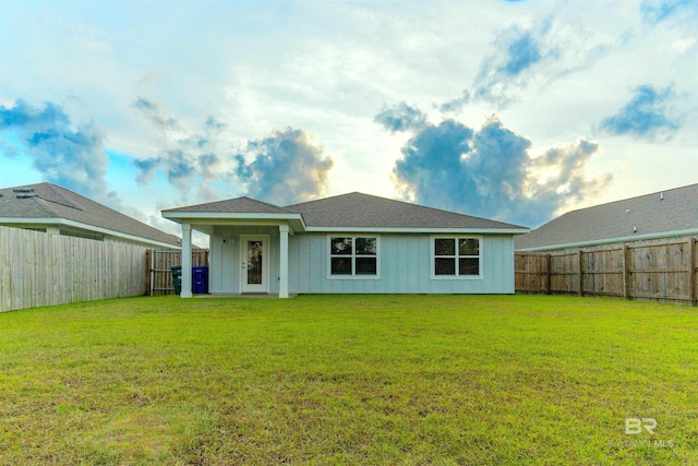 back of house with a lawn and a fenced backyard