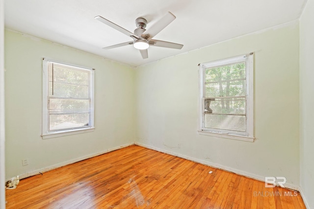 empty room featuring ceiling fan, a healthy amount of sunlight, and hardwood / wood-style floors