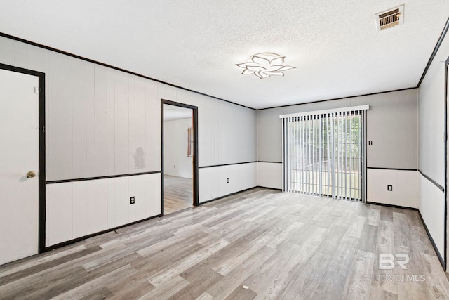 spare room featuring ornamental molding, a textured ceiling, and light hardwood / wood-style floors