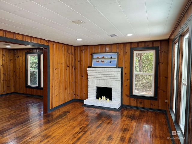 7121 N Century Blvd, Century, FL 32535 - unfurnished living room featuring hardwood / wood-style flooring, wood walls, a fireplace, baseboards, and recessed lighting