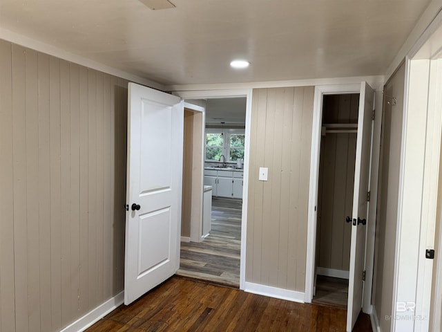 7121 N Century Blvd, Century, FL 32535 - unfurnished bedroom featuring dark wood-style flooring, wooden walls, baseboards, a sink, and a closet