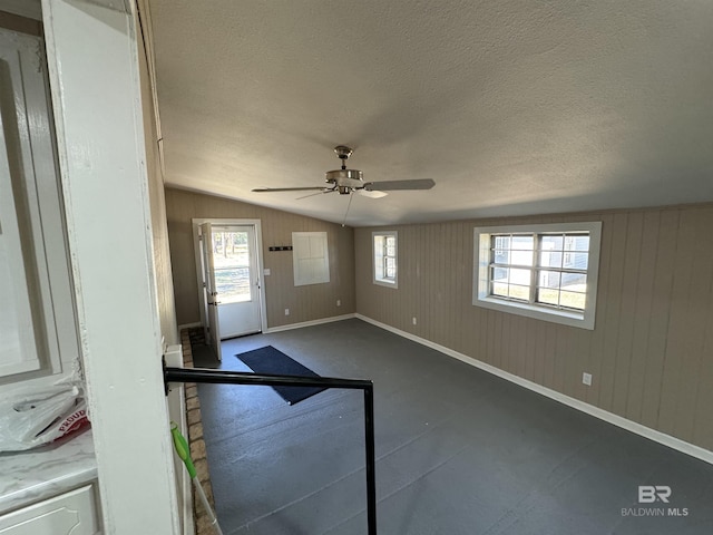 7121 N Century Blvd, Century, FL 32535 - unfurnished living room featuring ceiling fan, lofted ceiling, baseboards, plenty of natural light, and a textured ceiling