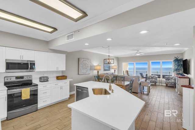 26200 Perdido Beach Blvd Unit 1403, Orange Beach, AL 36561 - kitchen featuring stainless steel appliances, light countertops, light wood-type flooring, open floor plan, and ornamental molding