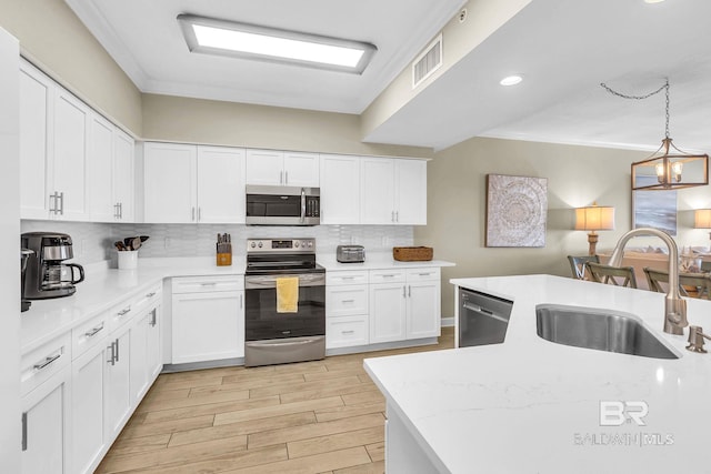 26200 Perdido Beach Blvd Unit 1403, Orange Beach, AL 36561 - kitchen with appliances with stainless steel finishes, tasteful backsplash, white cabinetry, light wood-type flooring, and hanging light fixtures