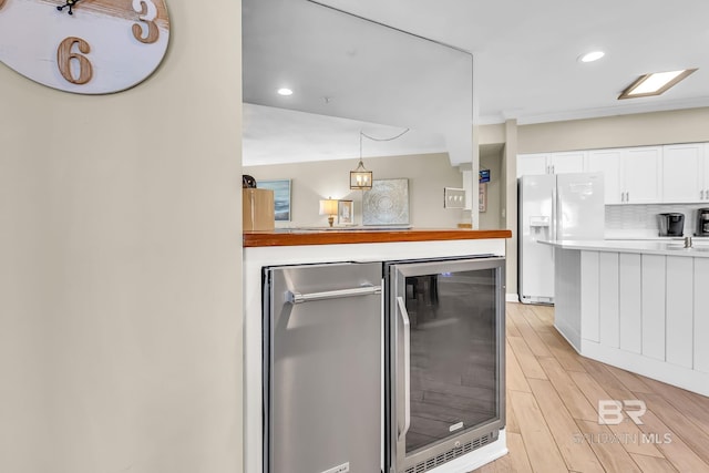 26200 Perdido Beach Blvd Unit 1403, Orange Beach, AL 36561 - kitchen featuring white fridge with ice dispenser, beverage cooler, white cabinets, light countertops, and light wood finished floors