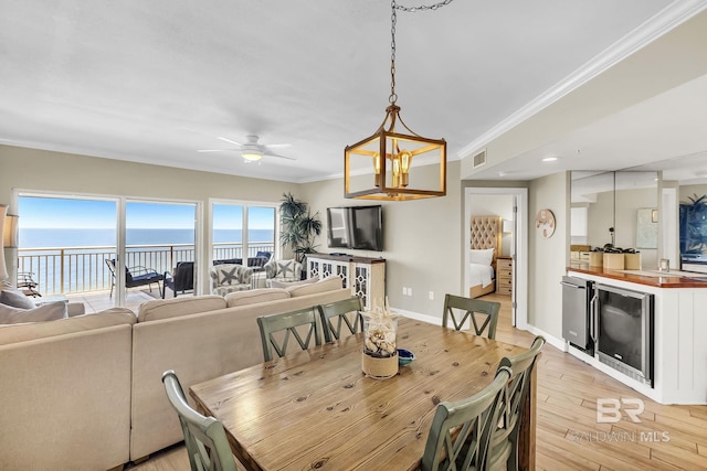 26200 Perdido Beach Blvd Unit 1403, Orange Beach, AL 36561 - dining space with beverage cooler, light wood-type flooring, ceiling fan, a water view, and ornamental molding